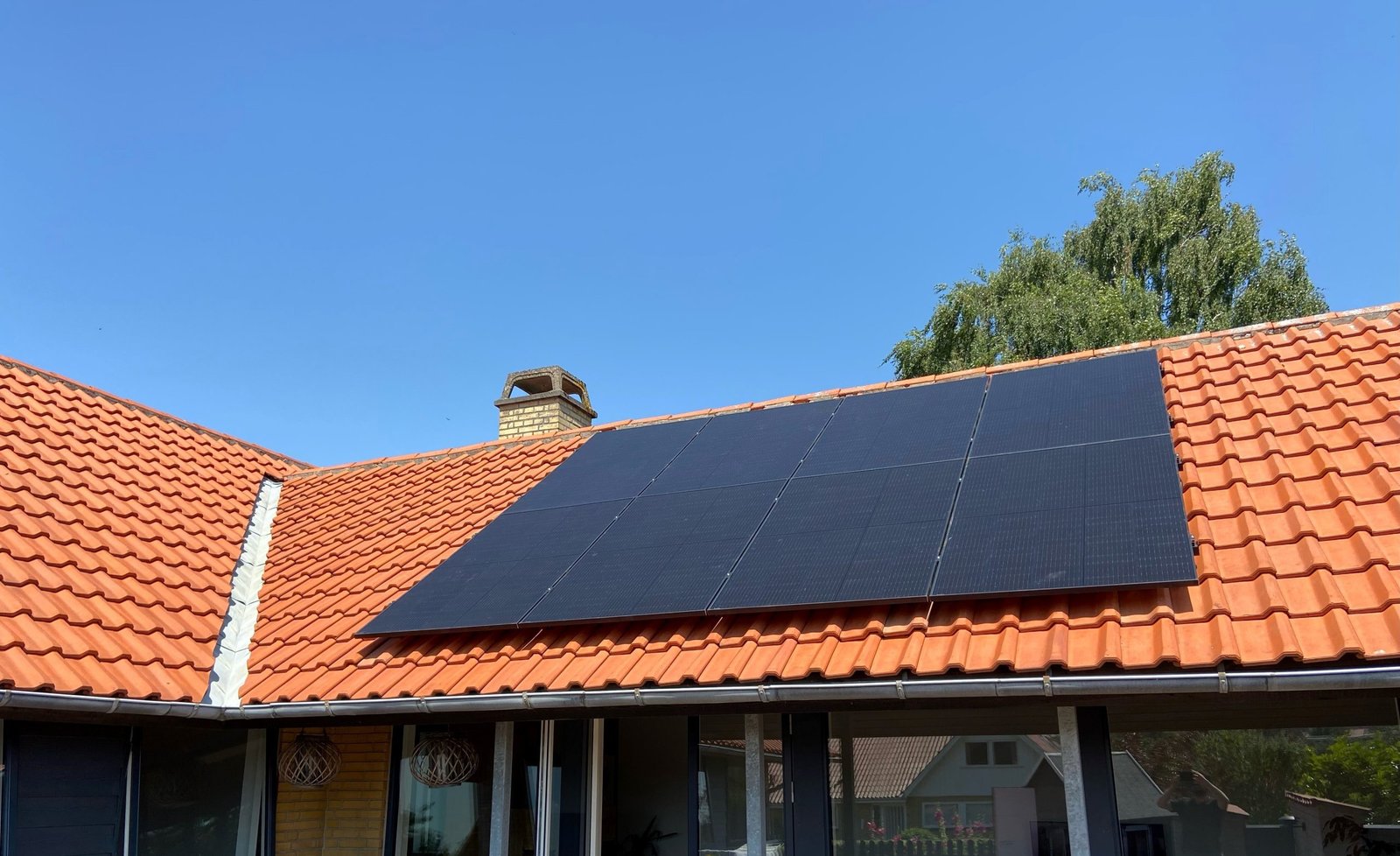 Et hus med rødt tegltag, der har 2 rækker med 8 solcellepaneler installeret
