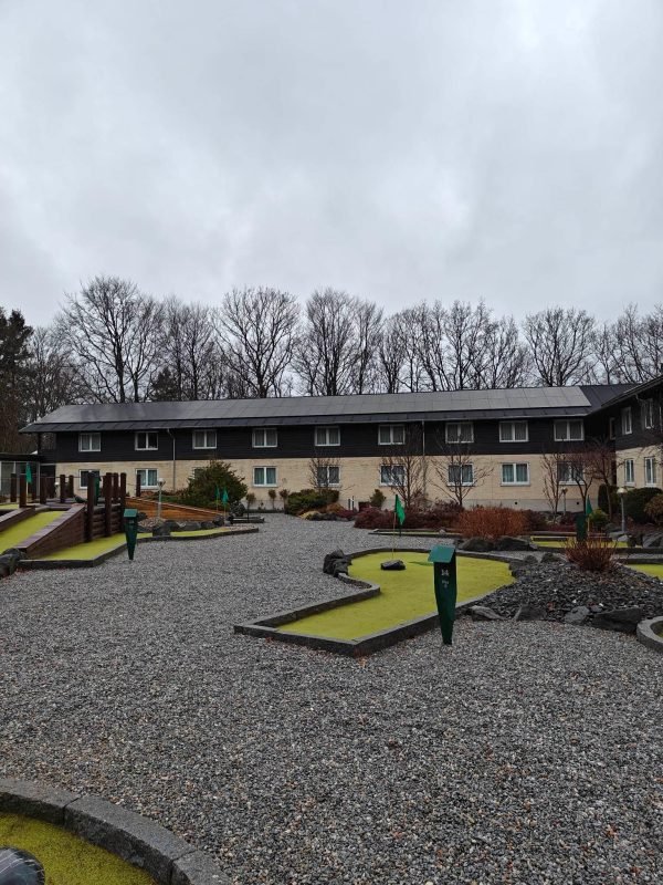 En minigolfbane med en bygning i baggrunden, der har solcellepaneler installeret på taget