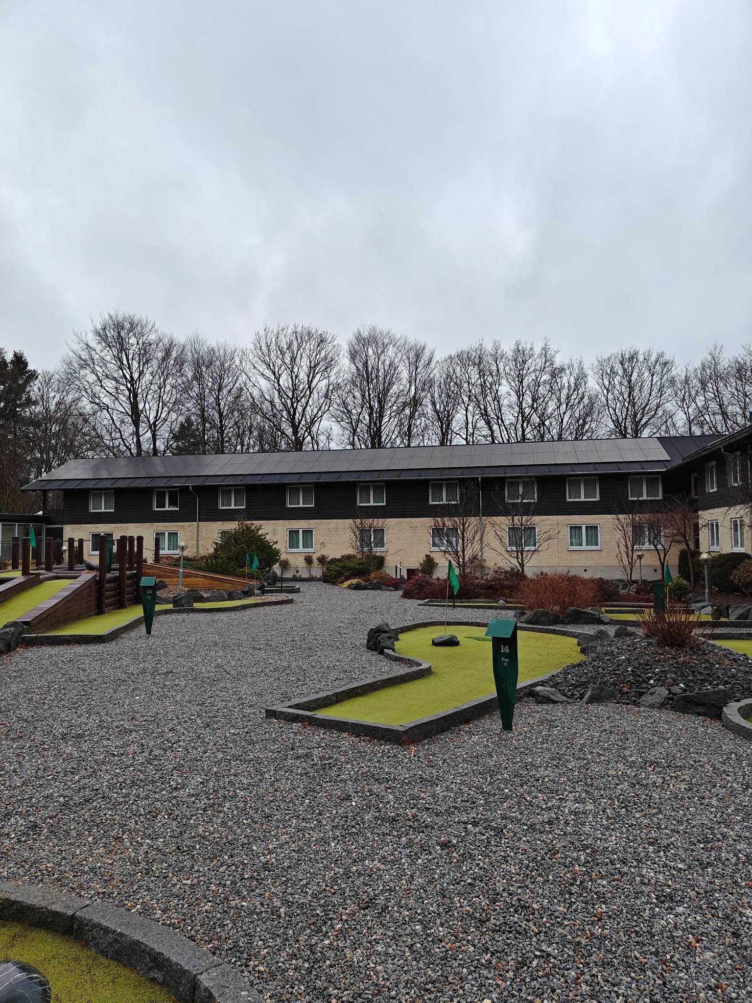 En minigolfbane med en bygning i baggrunden, der har solcellepaneler installeret på taget